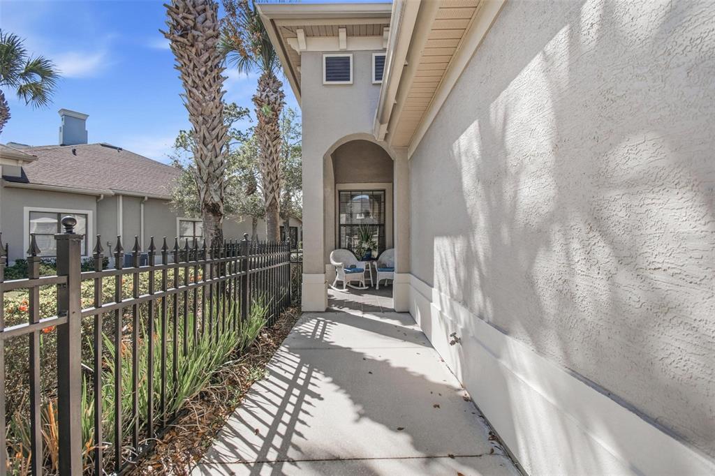 A concrete walkway leads to a covered entryway with two white chairs beside a house — 3 RIVER PARK DRIVE N, PALM COAST, FL
