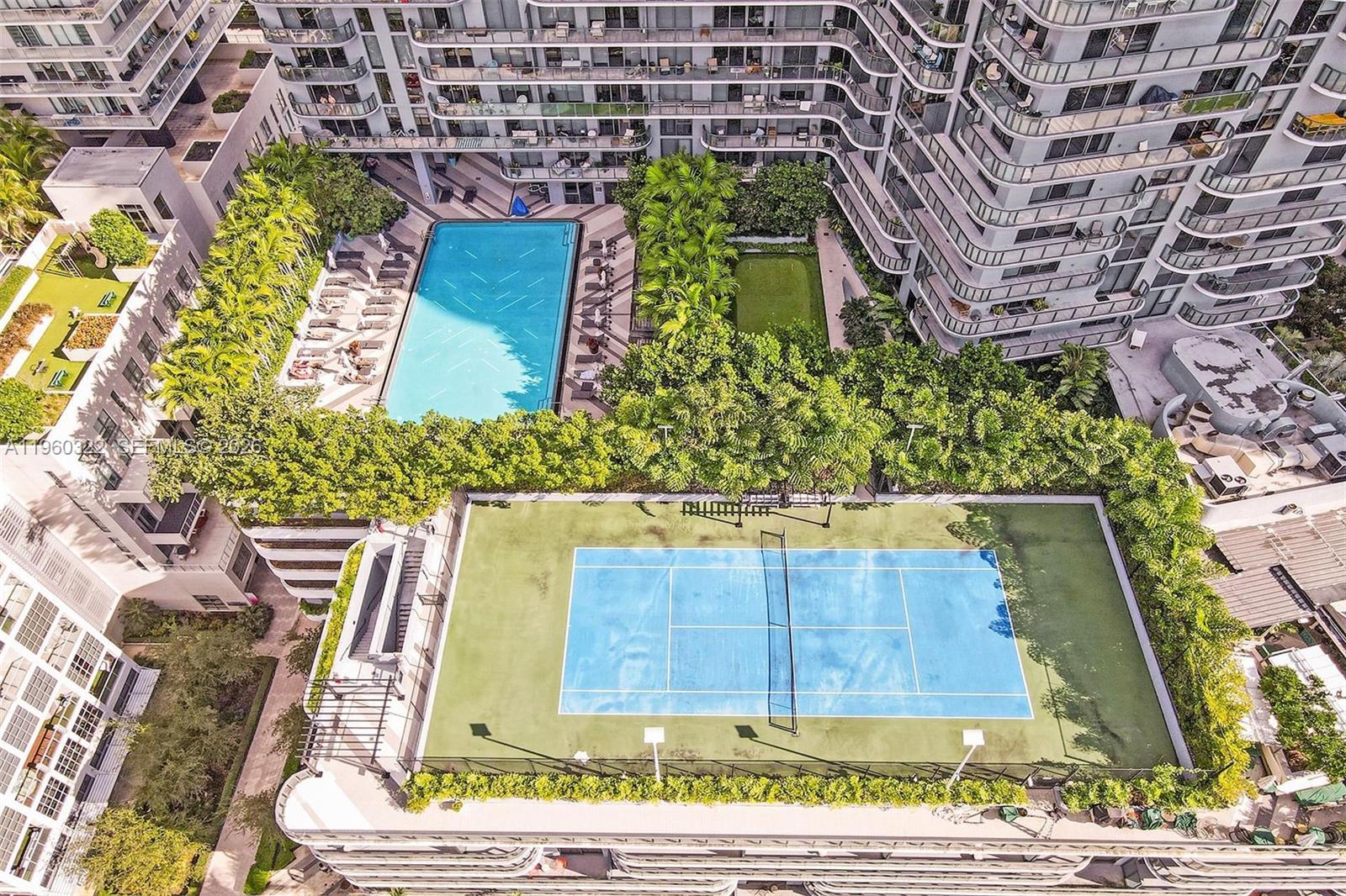 An aerial view shows a residential building complex with a tennis court, swimming pool, and landscaping — 121 NE 34th St # 2305, Miami FL 33137, MIAMI, FL