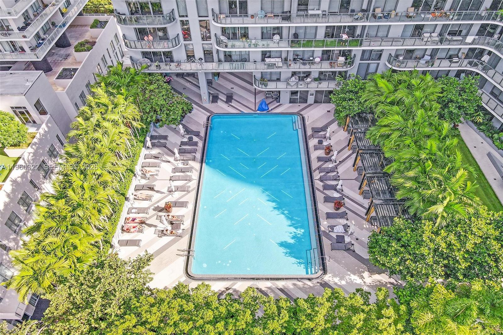 An aerial view shows a rectangular swimming pool surrounded by lounge chairs and palm trees — 121 NE 34th St # 2305, Miami FL 33137, MIAMI, FL