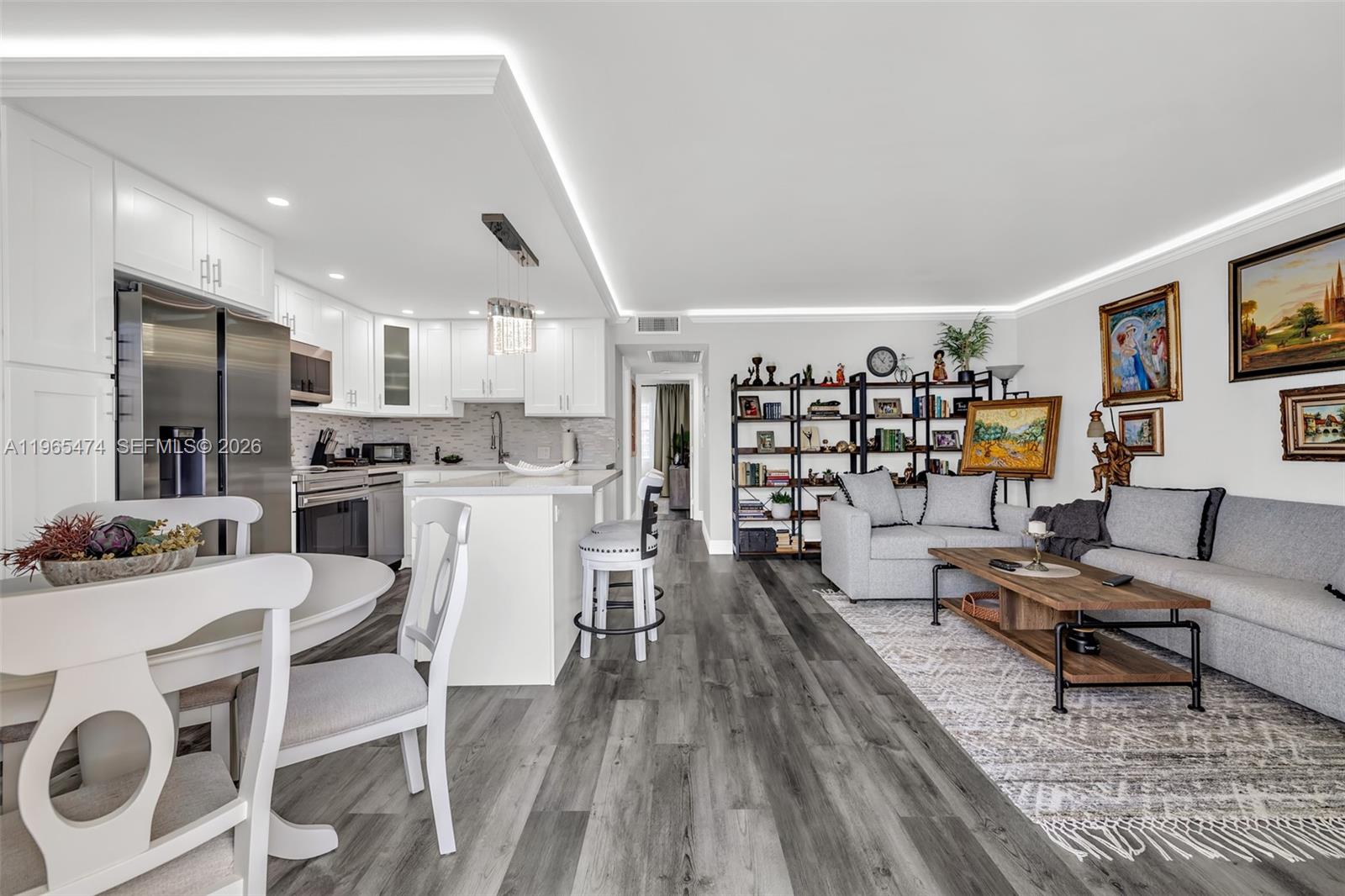 An open-concept kitchen and living area features white cabinetry, stainless appliances, and gray flooring — 152 Dorset D # 152, Boca Raton FL 33434, BOCA RATON, FL