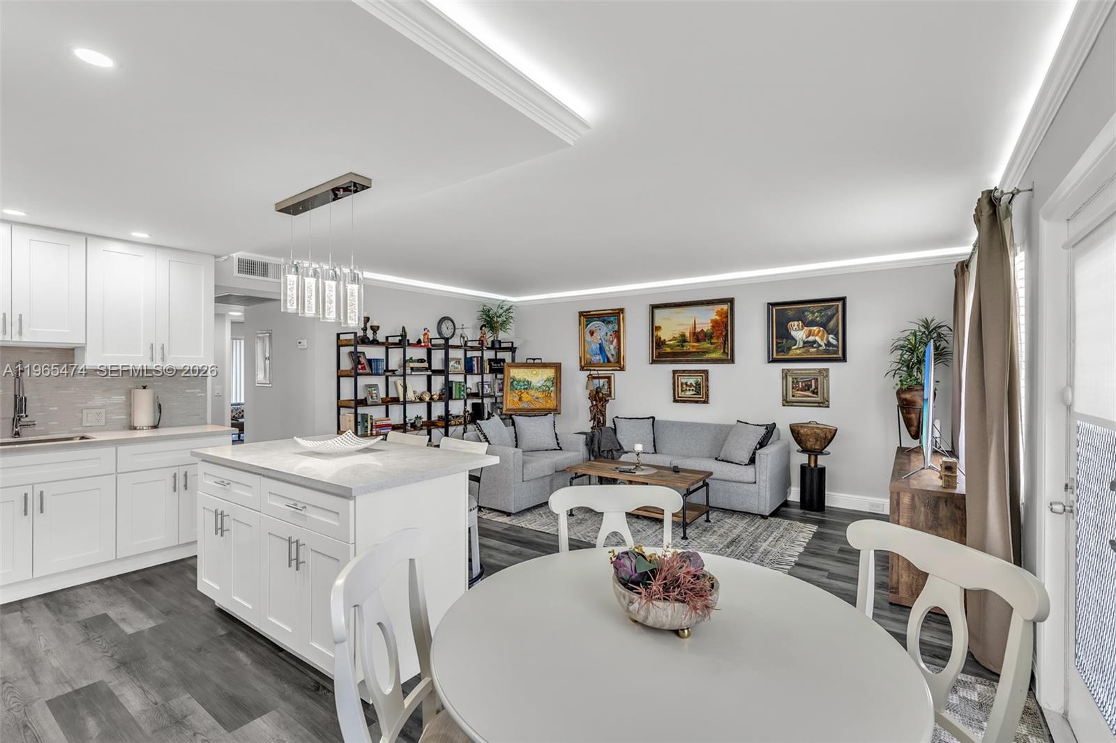 An open-concept kitchen and living area features white cabinetry, a central island, and gray flooring — 152 Dorset D # 152, Boca Raton FL 33434, BOCA RATON, FL