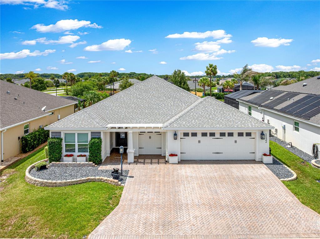 An exterior view of a single-story house with a paver driveway and a tiled roof — 1132 MAYNARD PATH, THE VILLAGES, FL