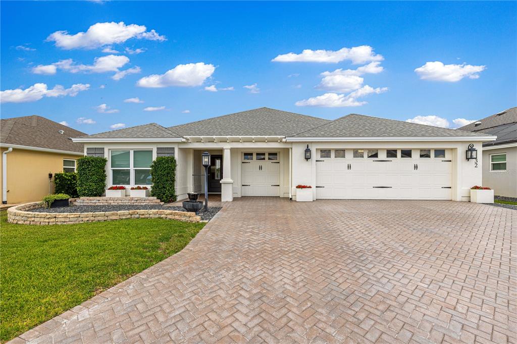 A single-story house features a white exterior, a three-car garage, and a paved driveway — 1132 MAYNARD PATH, THE VILLAGES, FL
