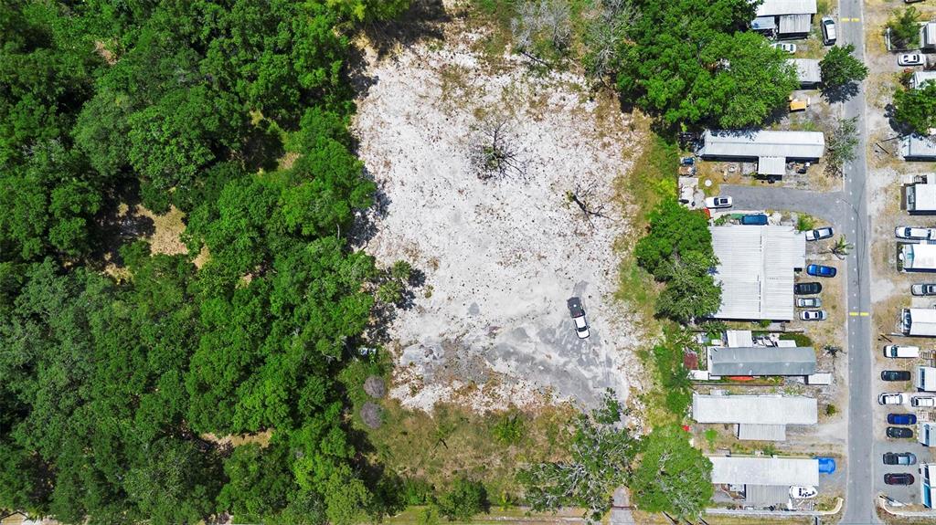 An aerial view shows a cleared, sandy vacant lot bordered by dense trees and mobile homes — 17520 EVANS TRAIL, ORLANDO, FL