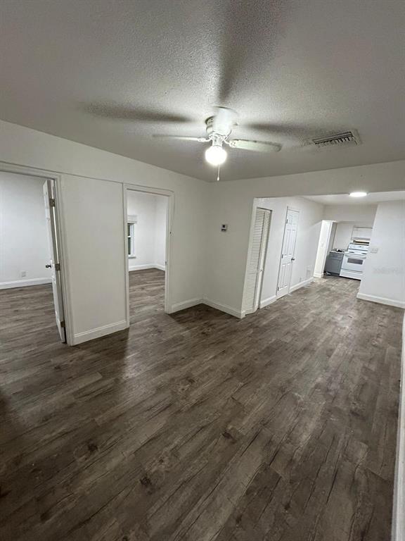An interior view showing a living area with wood-look flooring, a ceiling fan, and doorways — 8113 N ALASKA STREET, TAMPA, FL