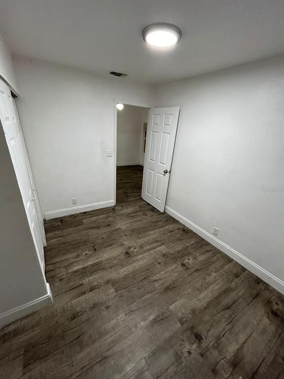 An empty bedroom features white walls, wood-look flooring, a ceiling light, and two white doors — 8113 N ALASKA STREET, TAMPA, FL