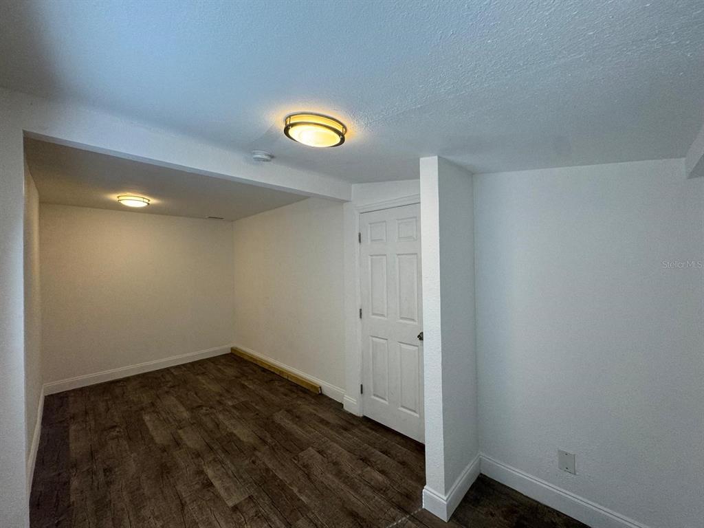 A small room with white walls, wood-look flooring, and two flush-mount ceiling lights — 8113 N ALASKA STREET, TAMPA, FL