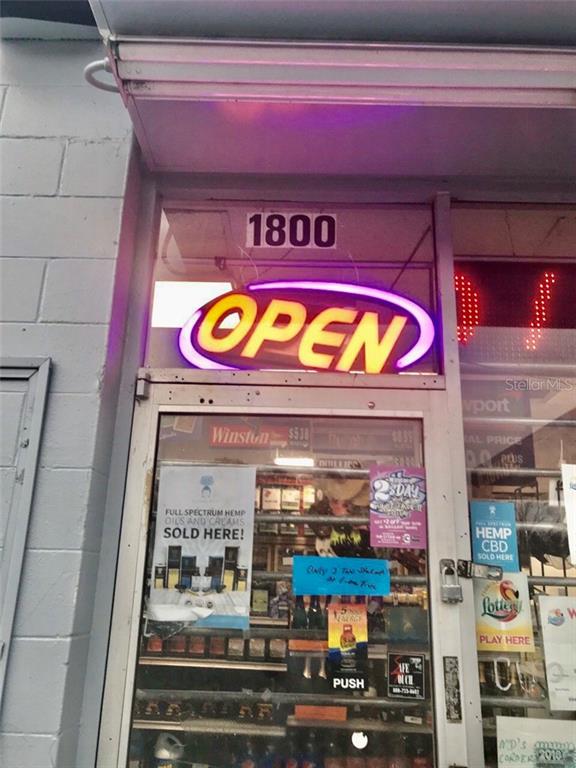 The exterior entrance of a commercial storefront features an illuminated open sign and glass door — 1800 S FRENCH AVENUE, SANFORD, FL
