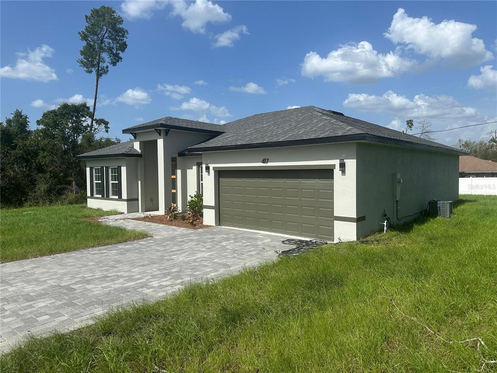 A single-story house with a gray garage door, light stucco walls, and a paved driveway — 417 MARION OAKS LANE, OCALA, FL
