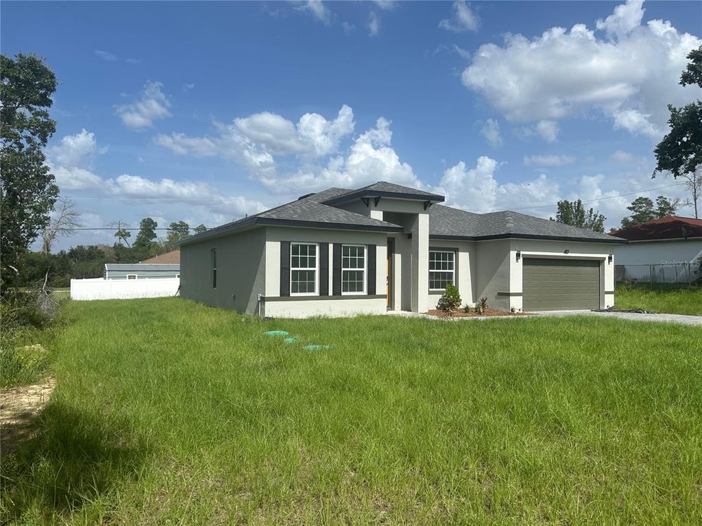 A single-story house with a gray exterior, dark roof, and an attached two-car garage — 417 MARION OAKS LANE, OCALA, FL
