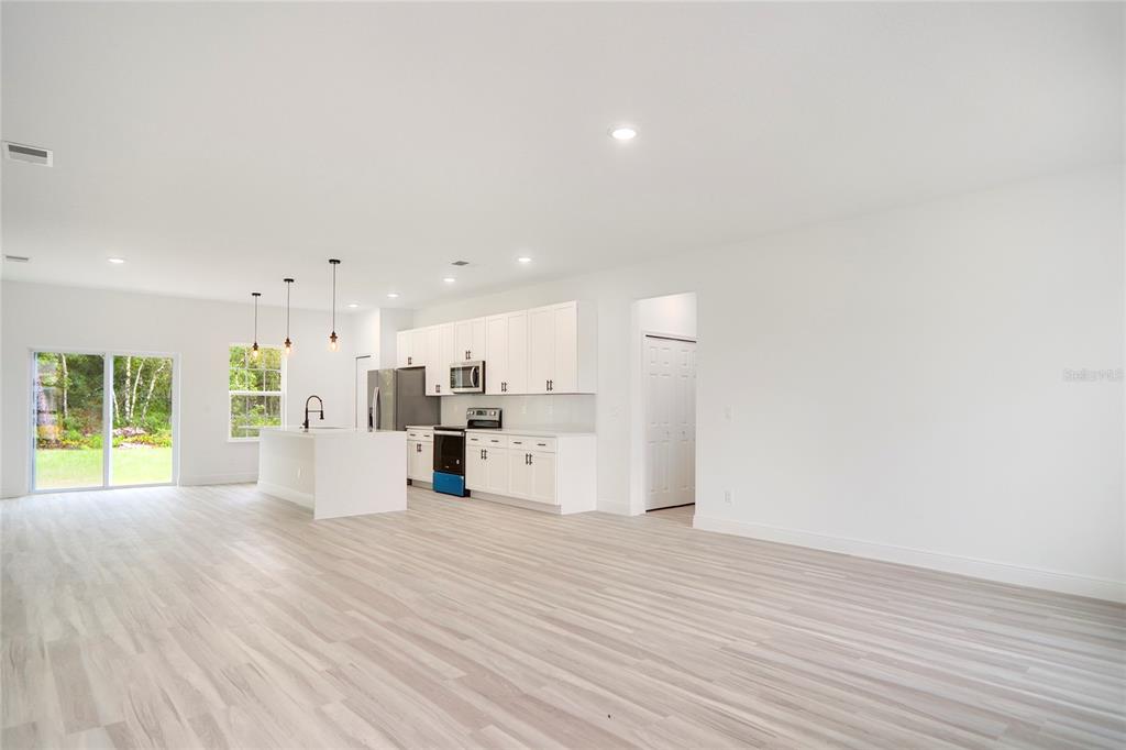 A bright, open-concept kitchen features white cabinetry, stainless steel appliances, and light wood-look flooring — 417 MARION OAKS LANE, OCALA, FL