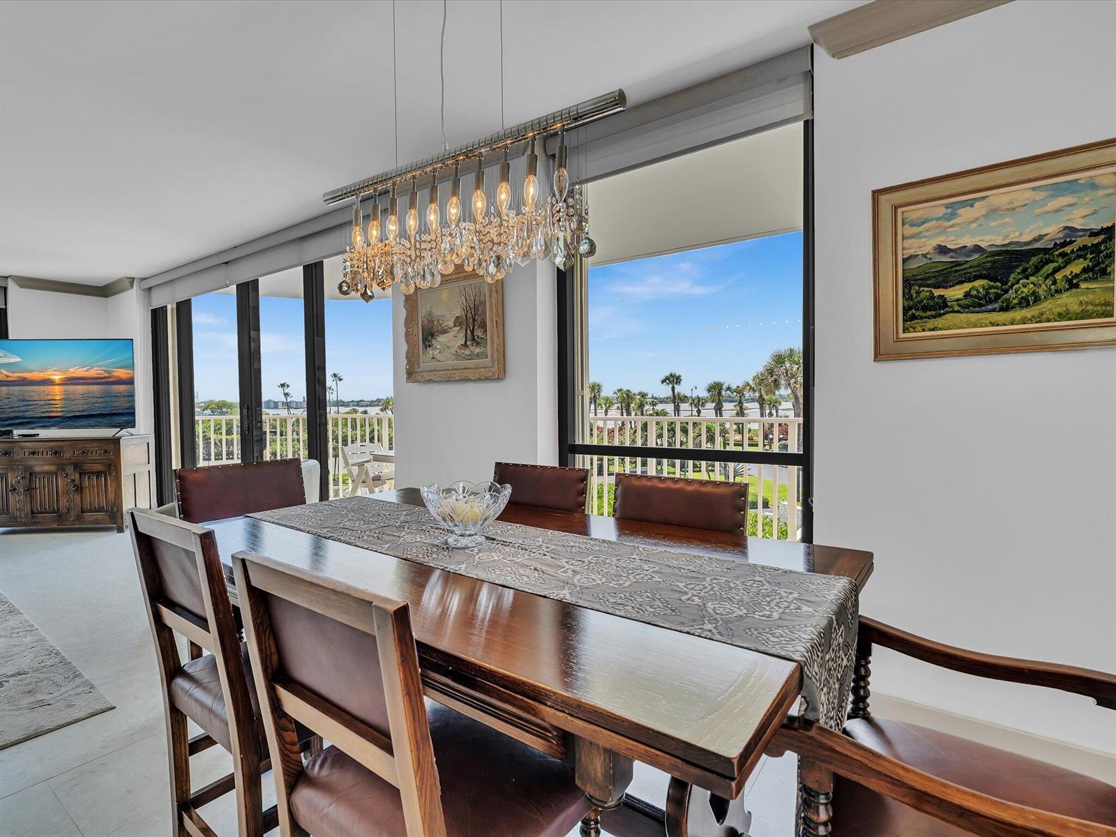 A dining room features a wooden table, leather chairs, a crystal chandelier, and balcony views — 3360 S Ocean Boulevard # 2a, Palm Beach FL 33480, PALM BEACH, FL