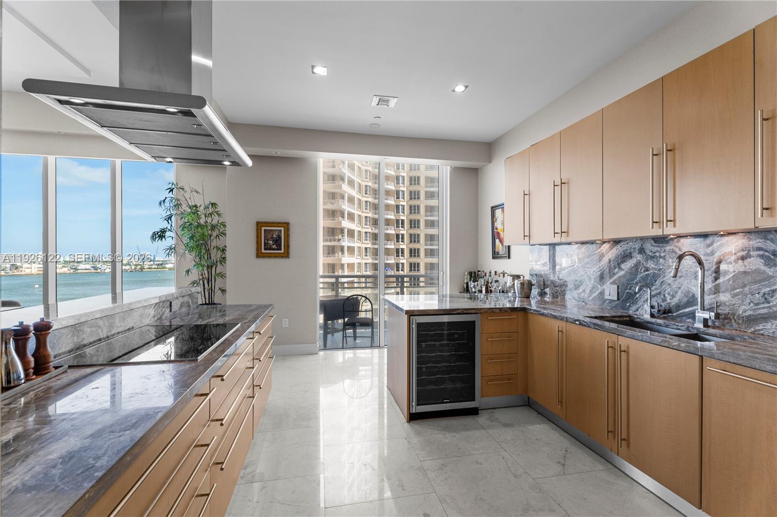 A modern kitchen features light wood cabinetry, marble countertops, stainless steel appliances, and waterfront views — 900 Brickell Key Blvd # 803, Miami FL 33131, MIAMI, FL