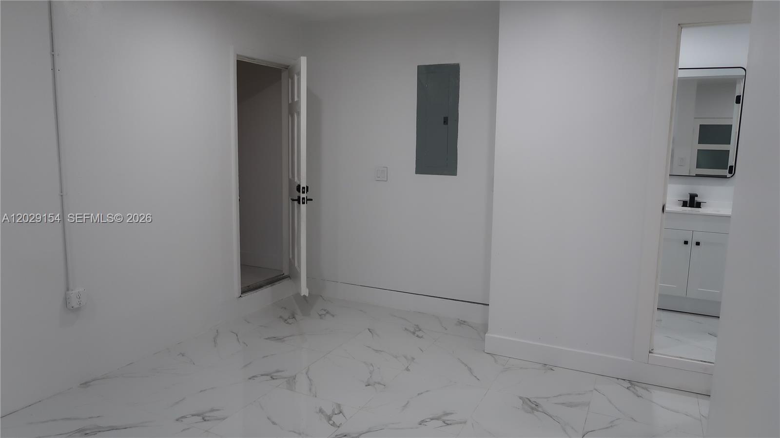 A white room with marble-patterned tile flooring, an open doorway, and an electrical panel — 8220 NW 199th St # 1, Hialeah FL 33015, HIALEAH, FL