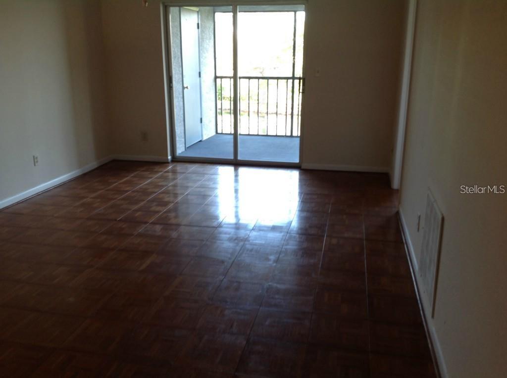 An empty room with parquet flooring, a ceiling fan, and a sliding glass door — 11201 122ND AVENUE UNIT L-232, LARGO, FL