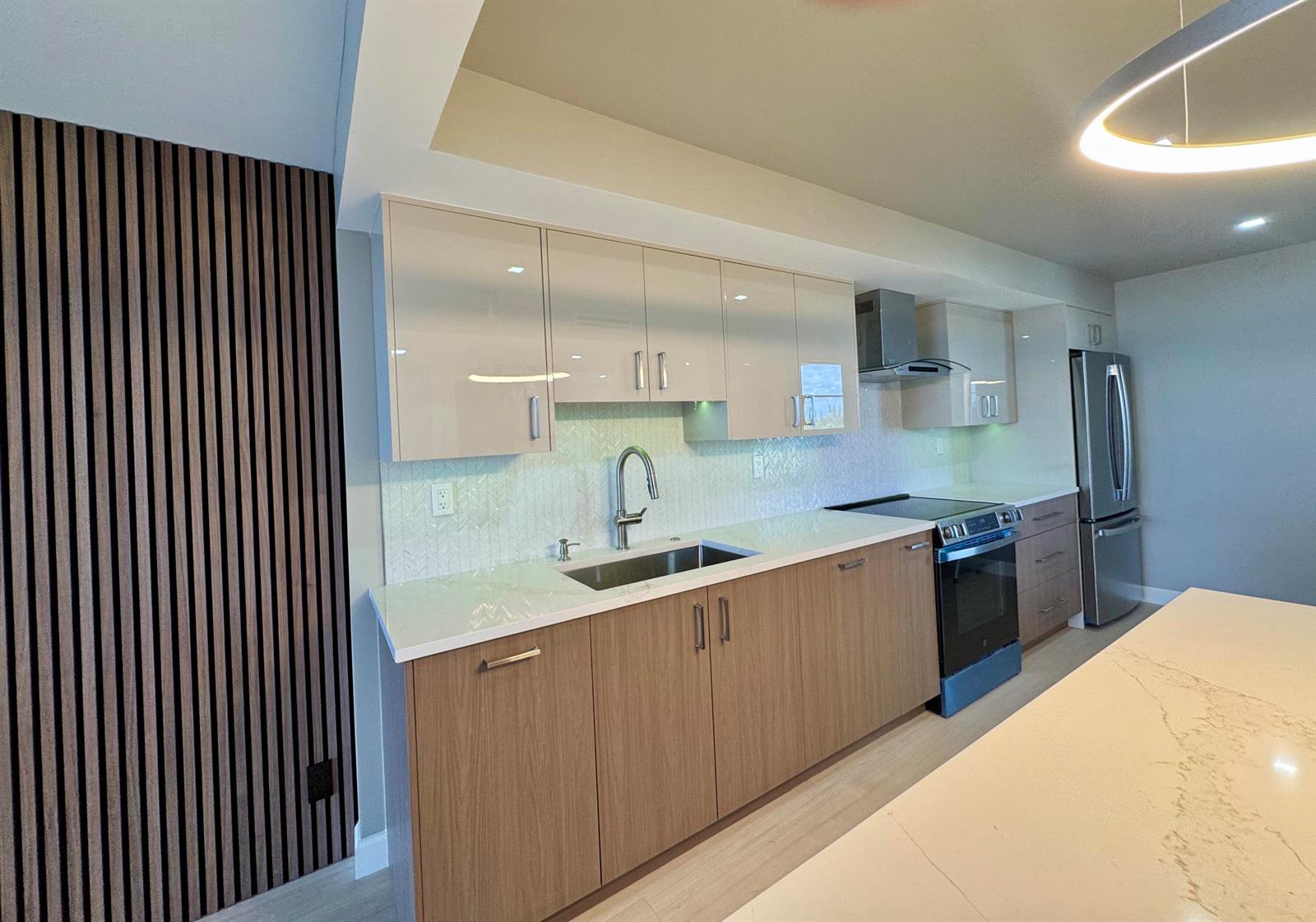A modern kitchen features two-tone cabinetry, a herringbone backsplash, and a wood-slat accent wall — 12 Royal Palm Way # 6030, Boca Raton FL 33432, BOCA RATON, FL