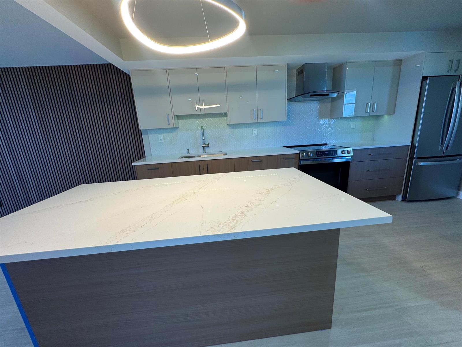 A modern kitchen features a white quartz island, two-toned cabinetry, and stainless steel appliances — 12 Royal Palm Way # 6030, Boca Raton FL 33432, BOCA RATON, FL