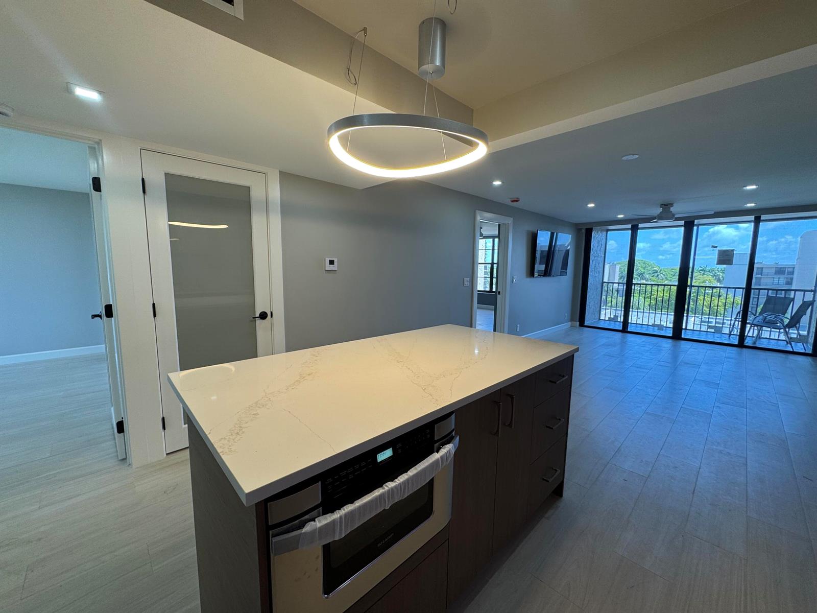 A kitchen island with a quartz countertop and built-in microwave sits in an open-concept room — 12 Royal Palm Way # 6030, Boca Raton FL 33432, BOCA RATON, FL