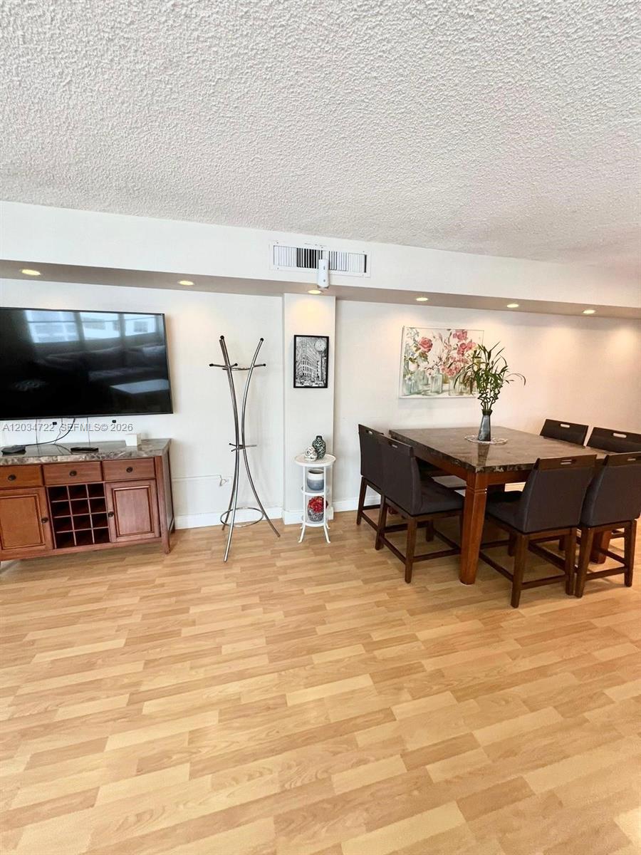 A dining area with a dark table and chairs sits next to a television console — 905 Brickell Bay Dr # 1422, Miami FL 33131, MIAMI, FL