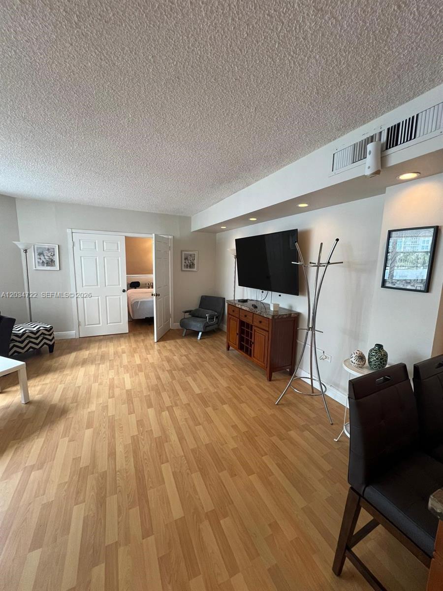 A living room features wood-look flooring, a wall-mounted television, and a doorway to a bedroom — 905 Brickell Bay Dr # 1422, Miami FL 33131, MIAMI, FL