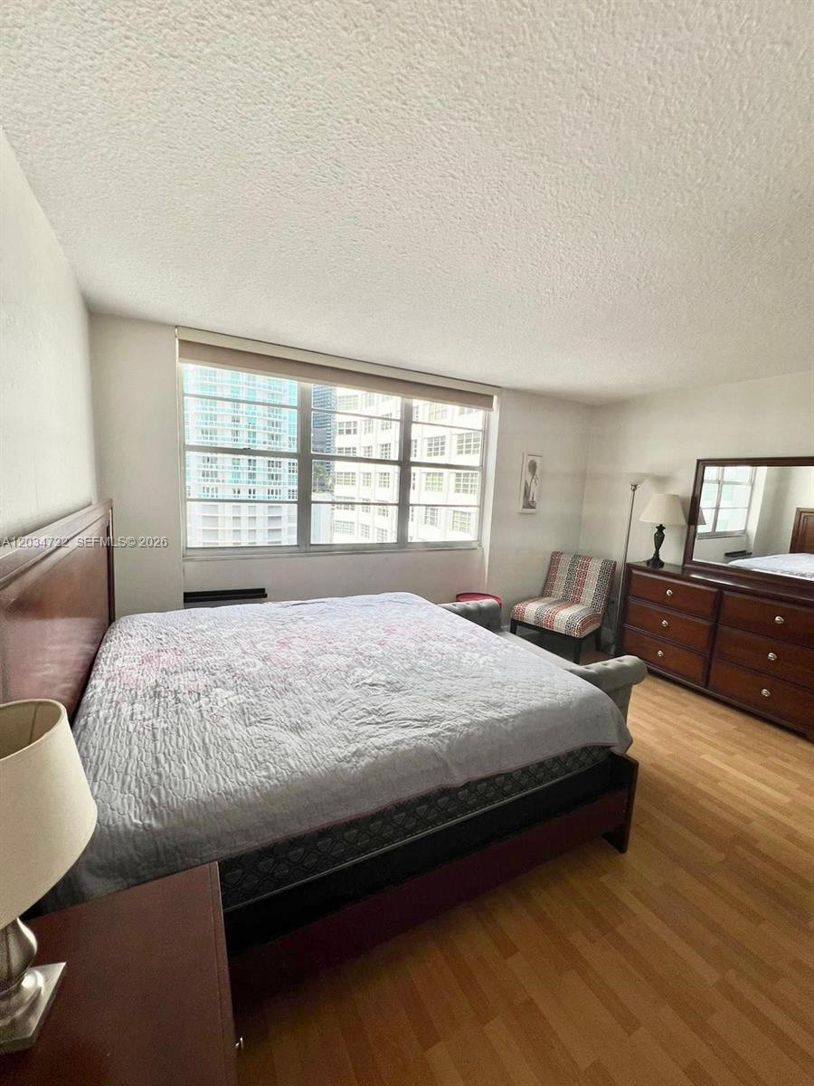 A bedroom features a large bed, a wooden dresser with a mirror, and city views — 905 Brickell Bay Dr # 1422, Miami FL 33131, MIAMI, FL