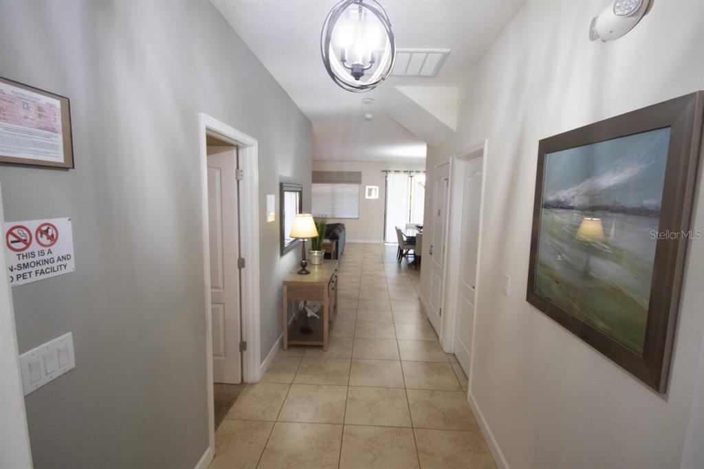 A tiled hallway leads from an entryway toward a living area with a dining space — 9162 WEDGE DRIVE, DAVENPORT, FL