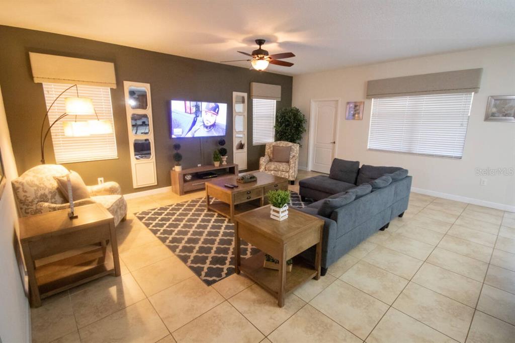 A living room features a dark accent wall, a sectional sofa, and tile flooring — 9162 WEDGE DRIVE, DAVENPORT, FL