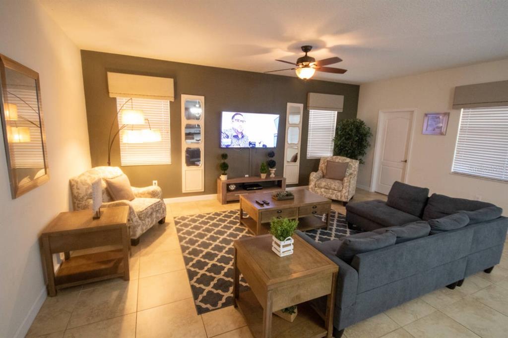 A living room features a dark accent wall, a gray sectional, and tile flooring — 9162 WEDGE DRIVE, DAVENPORT, FL