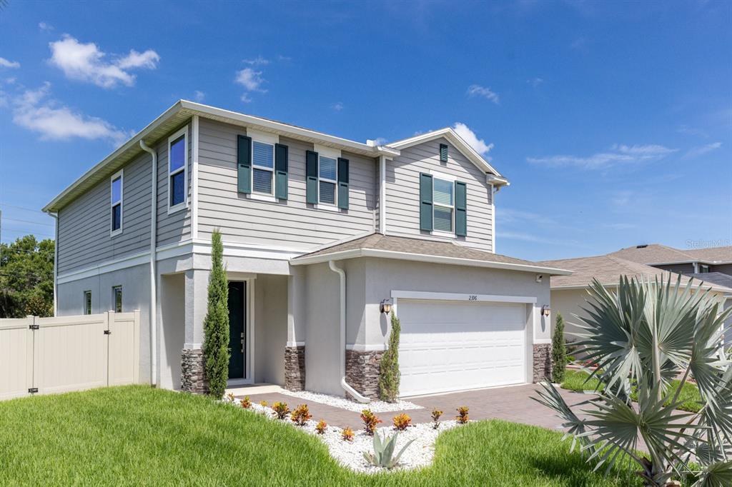 A two-story house with gray siding, a stone-accented facade, and a two-car garage — 2396 TWIN FLOWER LANE, SANFORD, FL