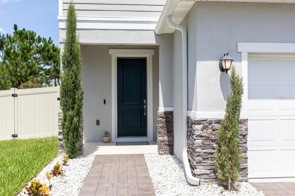 The exterior of a house features a dark front door, stone accents, and two tall shrubs — 2396 TWIN FLOWER LANE, SANFORD, FL