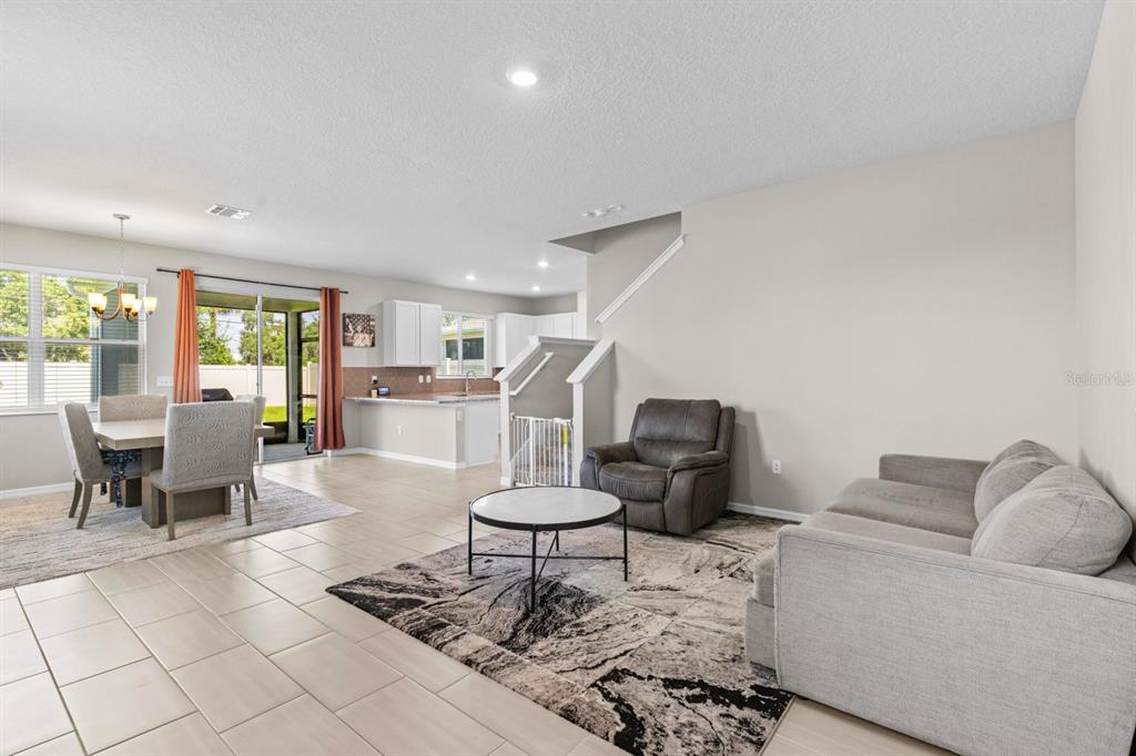 An open-concept living and dining area features tile flooring, a neutral color palette, and stairs — 2396 TWIN FLOWER LANE, SANFORD, FL