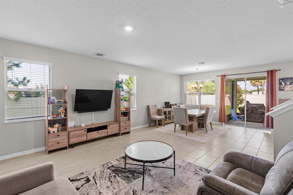 An open-concept living and dining area with tile flooring, a television console, and sliding doors — 2396 TWIN FLOWER LANE, SANFORD, FL