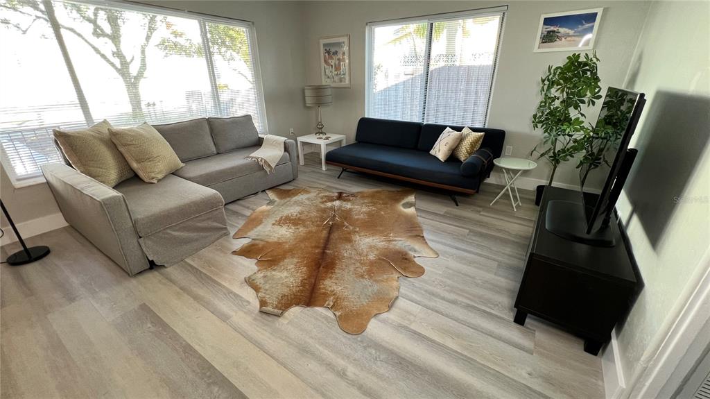 A living room features a grey sectional, a dark blue sofa, and a cowhide rug — 974 TENNESSEE LANE, SARASOTA, FL