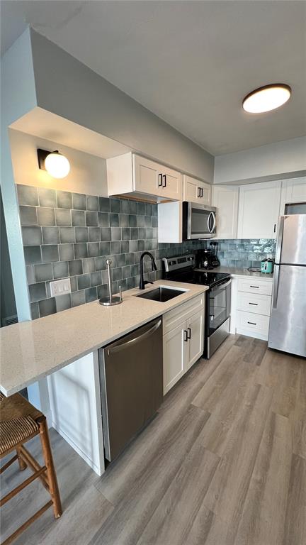 A kitchen features white cabinets, quartz countertops, a blue tiled backsplash, and stainless steel appliances — 974 TENNESSEE LANE, SARASOTA, FL
