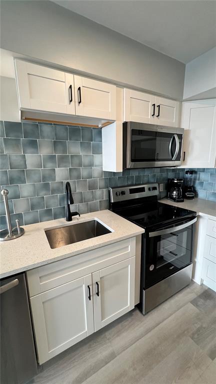 A kitchen features white cabinets, a stainless steel stove, a microwave, and blue-toned square tiles — 974 TENNESSEE LANE, SARASOTA, FL
