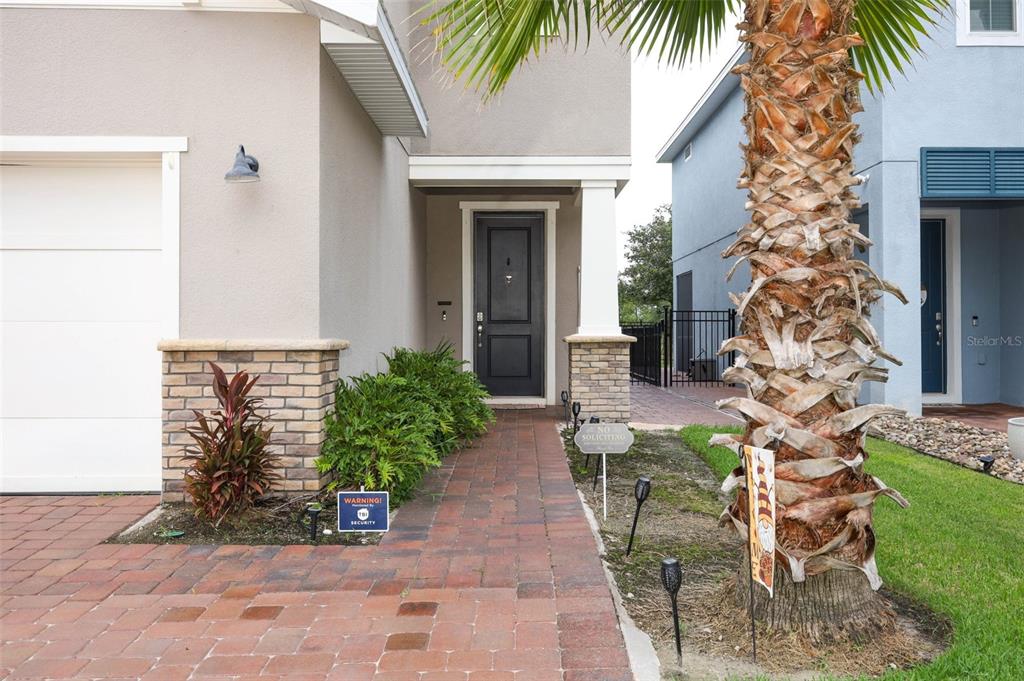A paved walkway leads to the front entrance of a house with a brick-accented porch — 3980 LIGHTNING COURT, SANFORD, FL