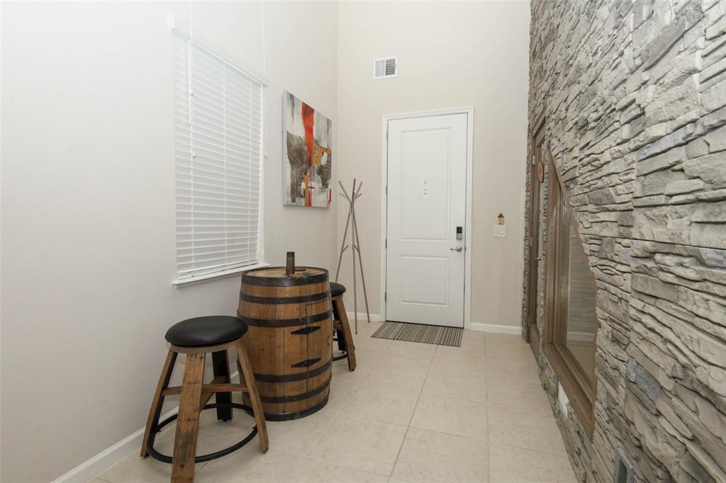 A high-ceilinged entryway features tile flooring, a stone accent wall, and a barrel-style table — 3980 LIGHTNING COURT, SANFORD, FL