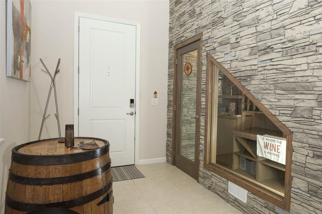 An entryway features a wine barrel table, a stone accent wall, and a glass-enclosed wine display — 3980 LIGHTNING COURT, SANFORD, FL