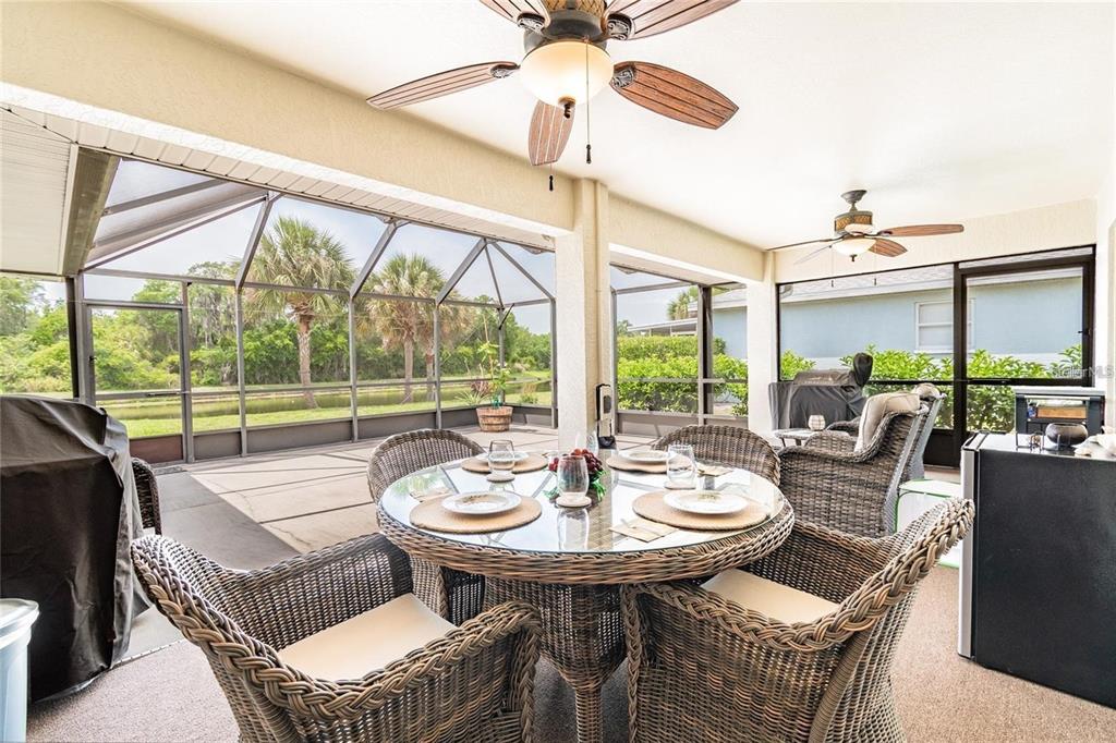 A screened-in patio features a glass-top dining table with wicker chairs and ceiling fans — 9501 27TH AVENUE E, PALMETTO, FL