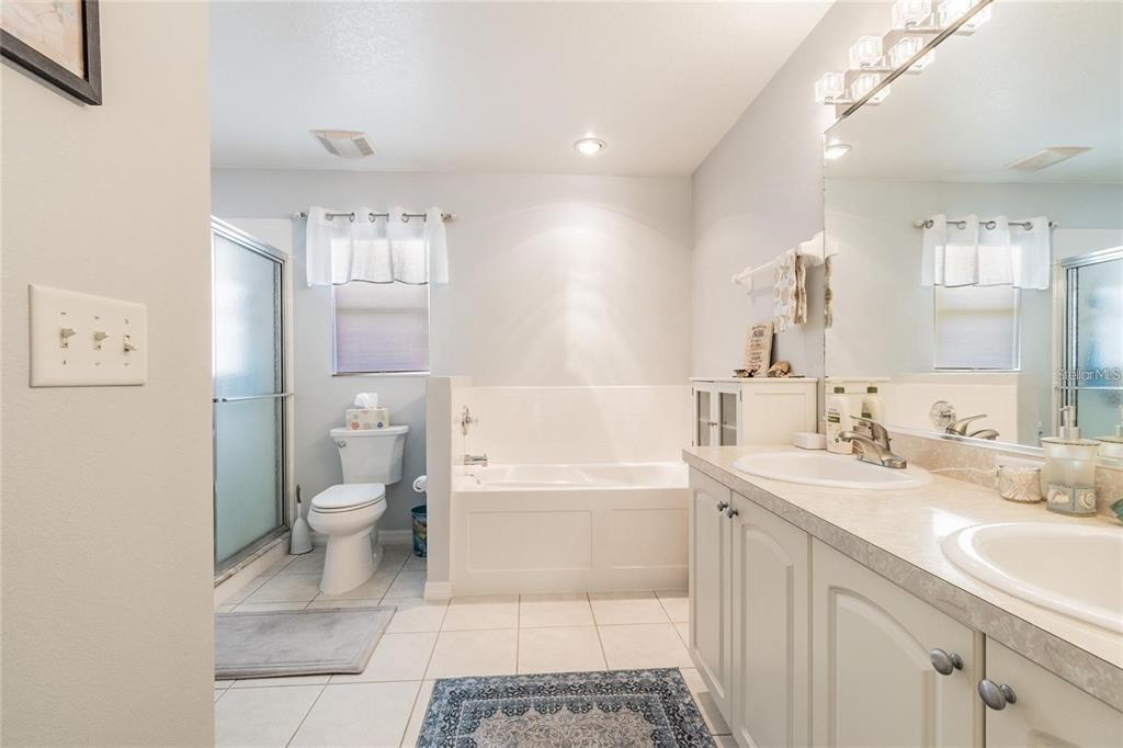 A bathroom features a white vanity with dual sinks, a soaking tub, and a toilet — 9501 27TH AVENUE E, PALMETTO, FL