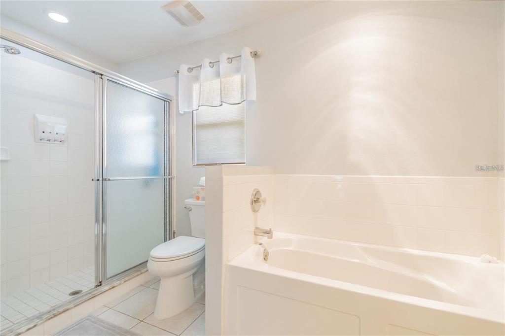 A bathroom features a glass-enclosed shower, a white toilet, and a built-in soaking tub — 9501 27TH AVENUE E, PALMETTO, FL