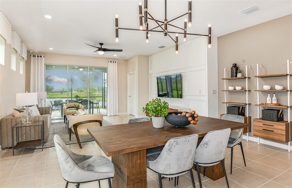 A dining area with a wooden table and chairs sits in front of a living room — 12514 ADOBE STREET, PARRISH, FL