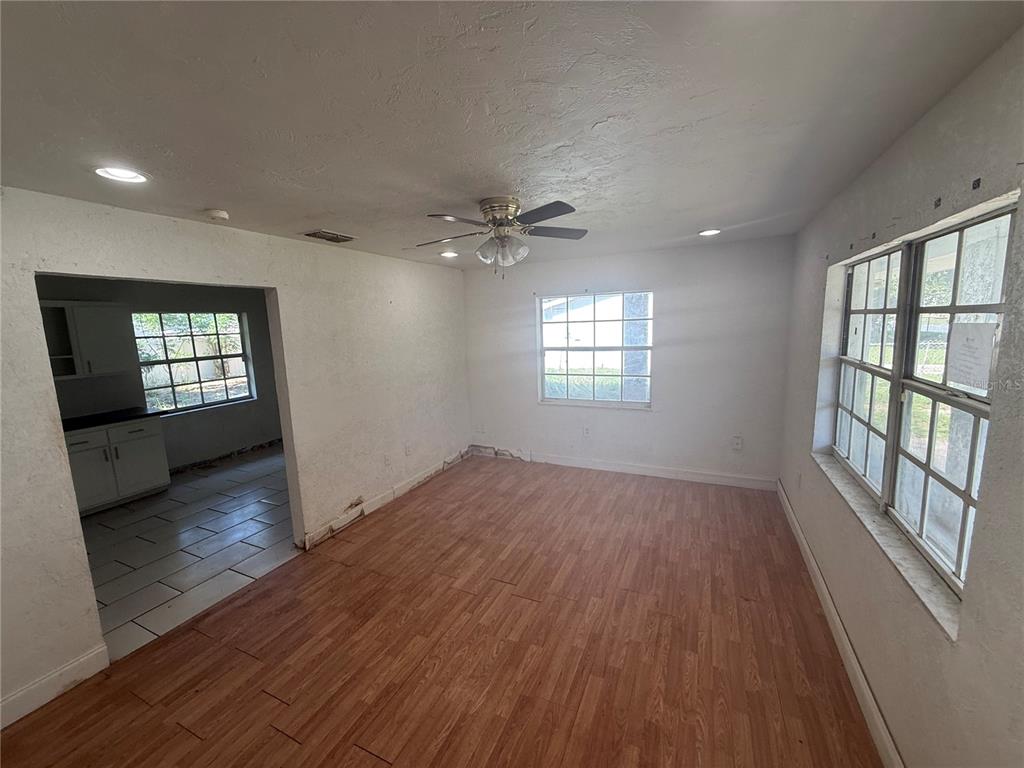 A living room with wood-look flooring, a ceiling fan, and windows looking into a kitchen — 2442 LILLY STREET, LAKE WALES, FL