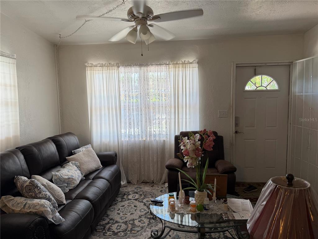 A living room features a dark leather sofa, an armchair, a ceiling fan, and curtains — 32 ROANOKE DRIVE UNIT 0, FORT MYERS, FL