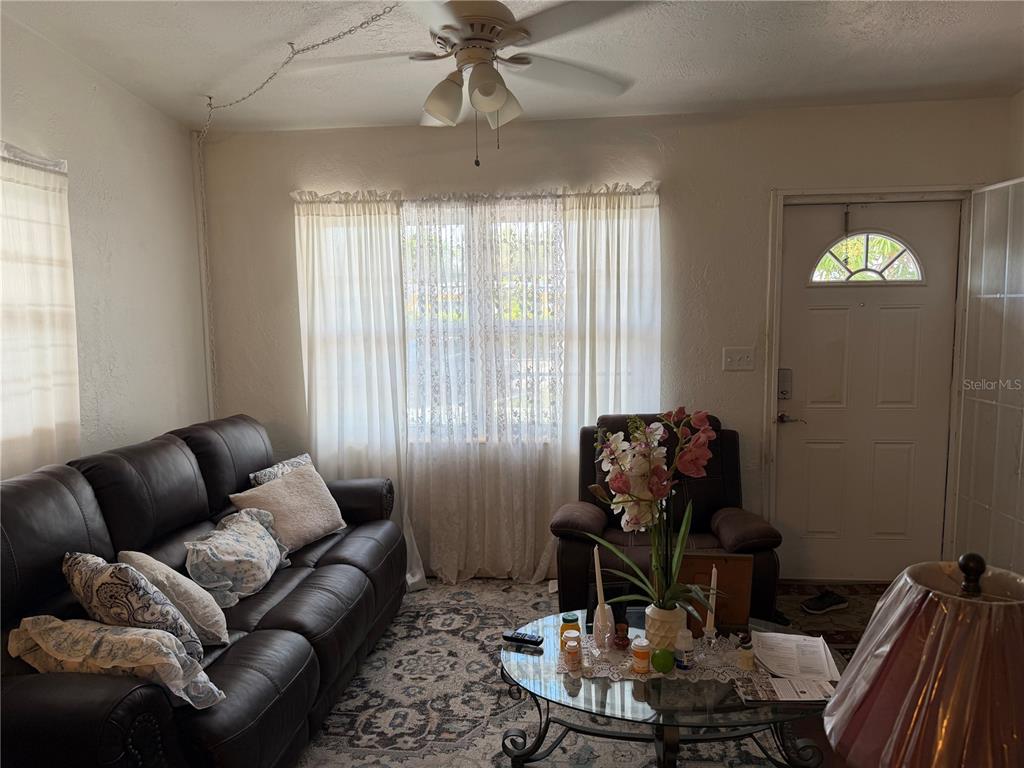 A living room features a dark leather sofa, a glass coffee table, and a ceiling fan — 32 ROANOKE DRIVE UNIT 0, FORT MYERS, FL