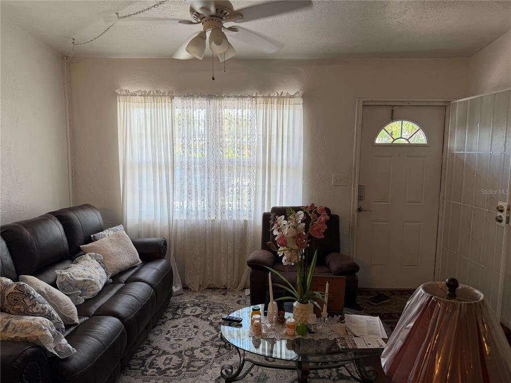A living room features a dark leather sofa, a recliner, and a glass coffee table — 32 ROANOKE DRIVE UNIT 0, FORT MYERS, FL