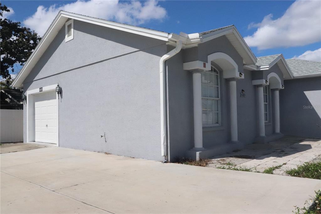 A gray single-story house features a white garage door, columns, and a concrete driveway — 5102 N MACDILL AVENUE, TAMPA, FL