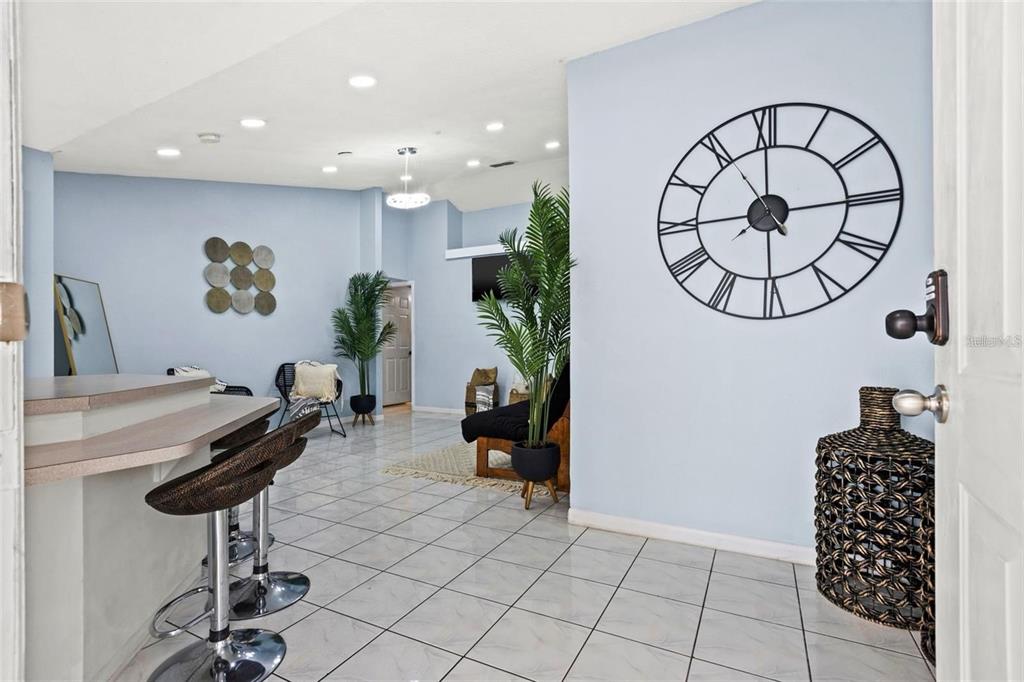 A tiled room features a breakfast bar, a large wall clock, and several potted plants — 5102 N MACDILL AVENUE, TAMPA, FL