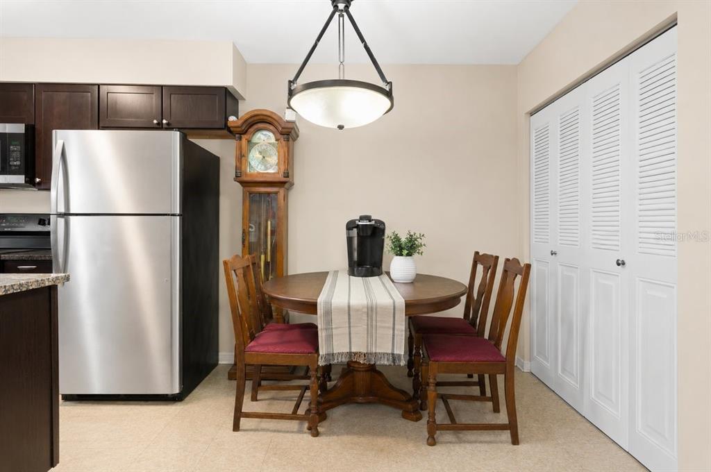 A dining area features a round wooden table with four chairs, a grandfather clock, and stainless-steel appliances — 1812 SW 70TH TERRACE, GAINESVILLE, FL
