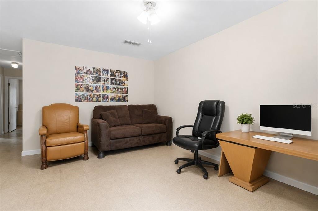 A room features a tan recliner, a brown sofa, a desk with a computer, and tile flooring — 1812 SW 70TH TERRACE, GAINESVILLE, FL